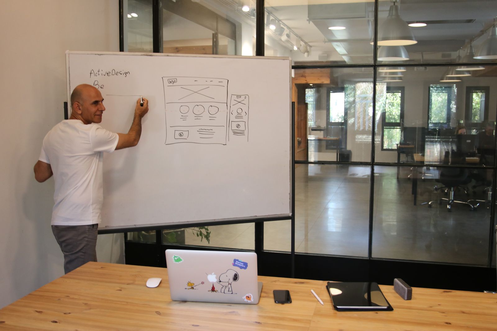 A designer sketching a website wireframe on a whiteboard during a planning meeting