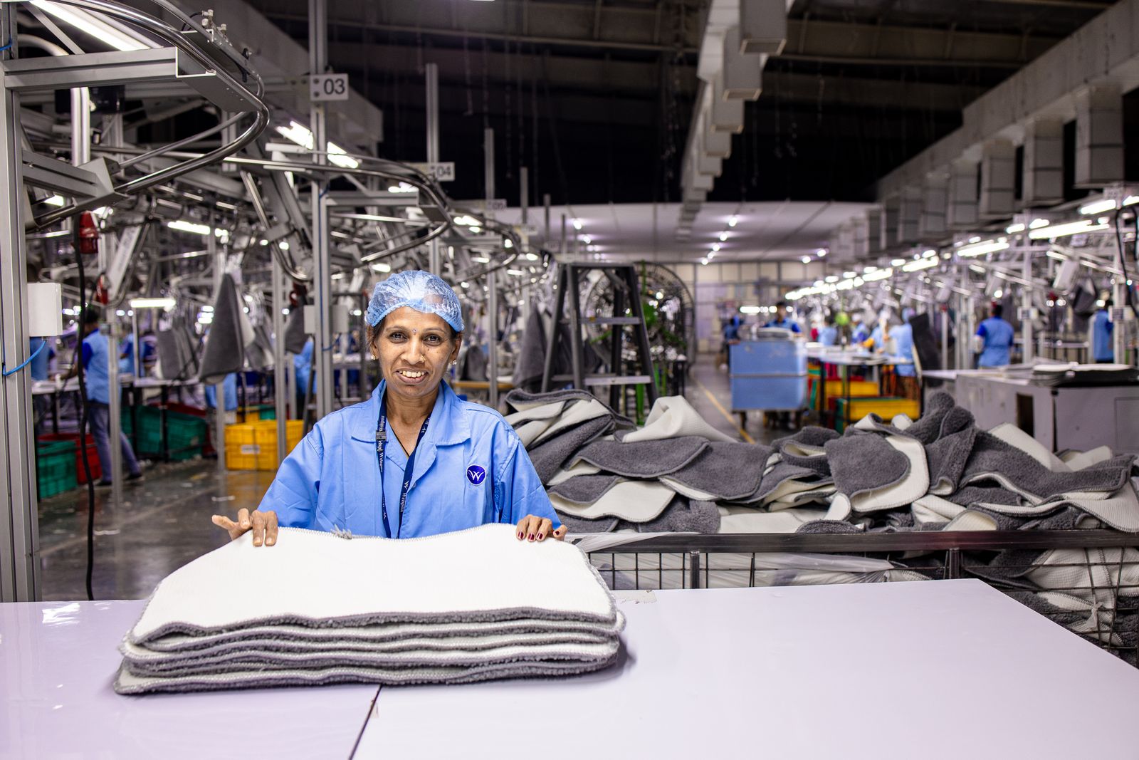 Factory worker smiling on a production floor, representing new manufacturing jobs