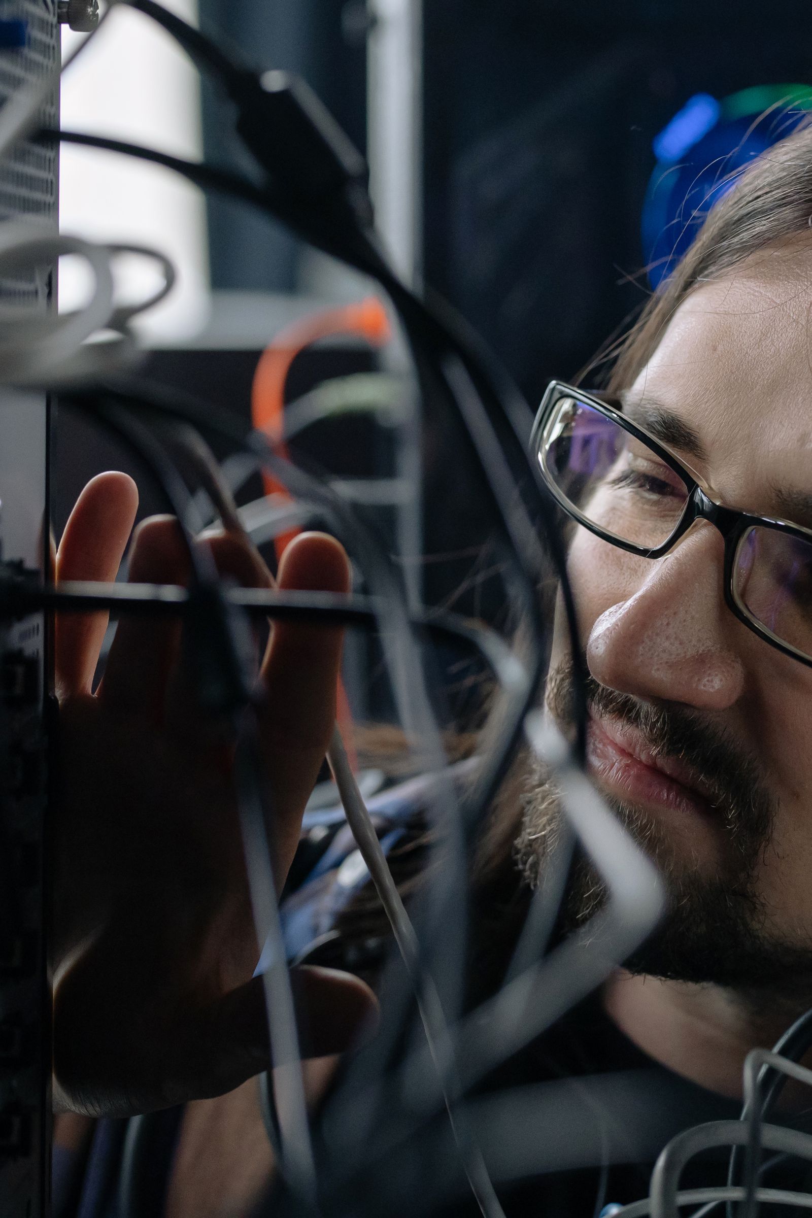 A technician closely inspecting tangled server cables during maintenance