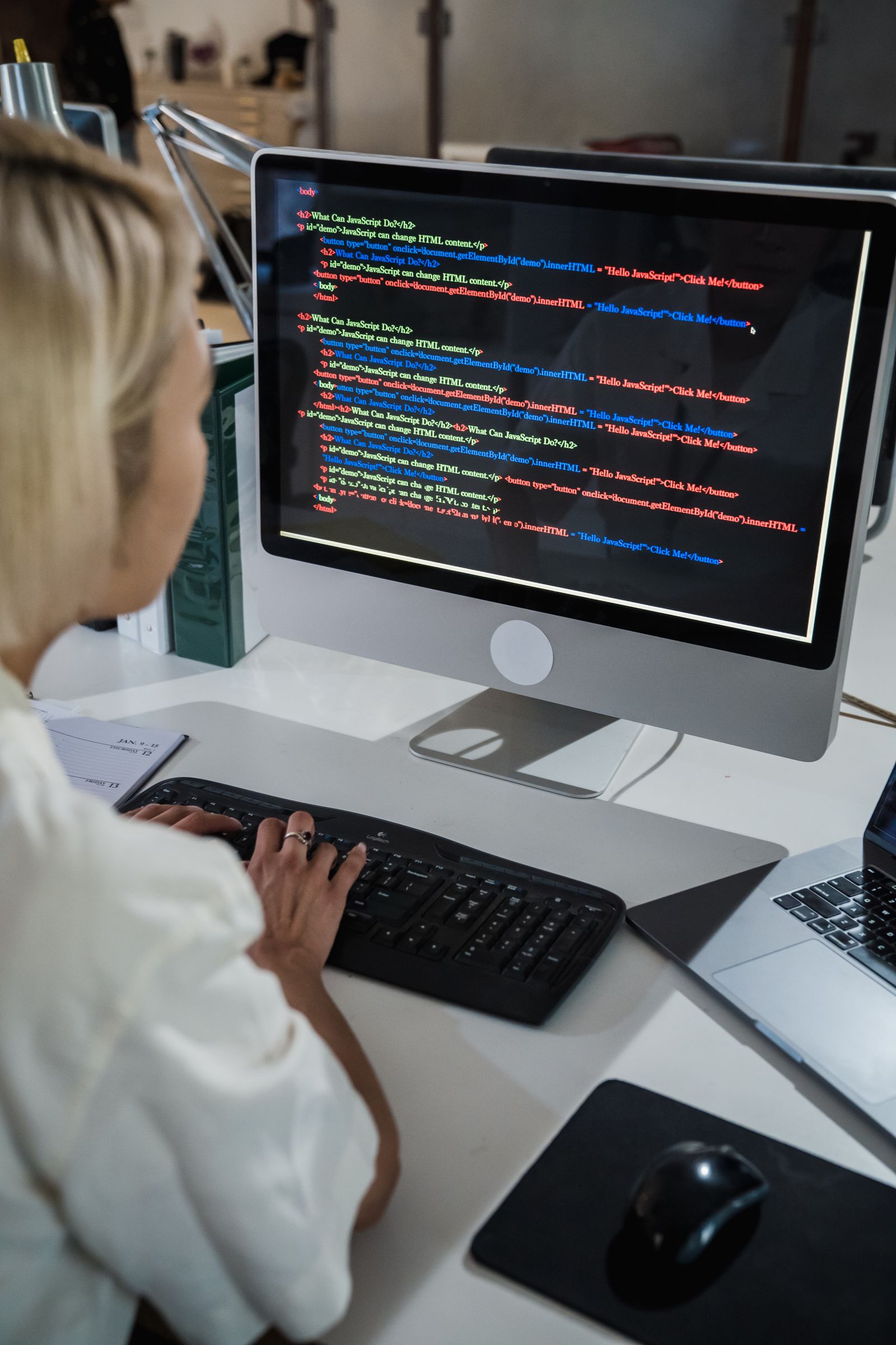 Web developer working on HTML and JavaScript code on a desktop monitor